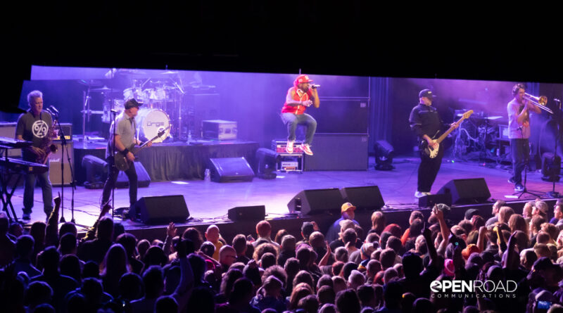 The band The Urge in concert. At a distance with some of the crowd watching them.
