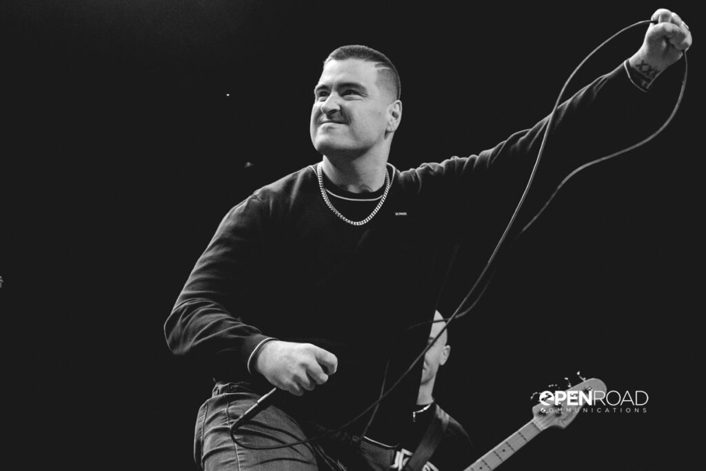 Tommy, lead singer of Slugger in black and white gesturing 