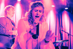 Boys Go To Jupiter' Jess Kantorowitz singing and bathed in pink hues