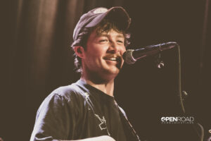 Brenn! smiles while standing behind the microphone