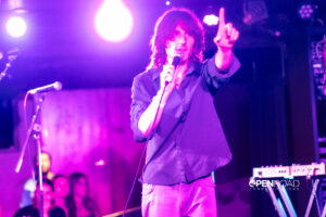 Foxtide's Elijah Gibbins-Croft hold a finger up while singing on stage at their St. Louis concert.