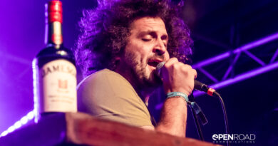 Andy Frasco sings into the mic. The ever-present bottle of whiskey on the piano